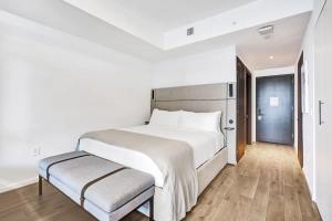 a white bedroom with a large bed and a bench at Luxury Miami Studio 27th Floor in Miami