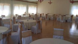 uma sala cheia de mesas e cadeiras com toalha de mesa branca em Laguna Guesthouse em Bela Crkva