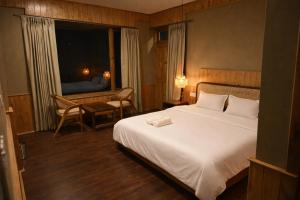 een slaapkamer met een wit bed, een bureau en een raam bij Odbostays Manali in Haripūr