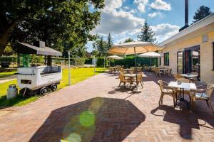 een patio met tafels en parasols en een grill bij Het Heideverblijf in Heerlen