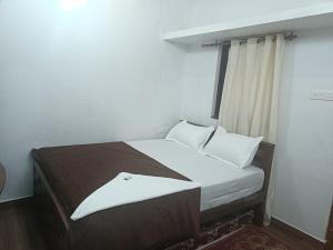 a bedroom with a bed with white sheets and pillows at Eva homes in Vagamon