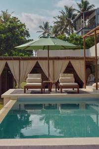 een zwembad met 2 ligstoelen en een parasol bij Soul Temple Boutique Hotel ADULTS ONLY in Ahangama