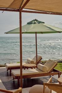 een groep stoelen en een parasol op het strand bij Soul Temple Boutique Hotel ADULTS ONLY in Ahangama