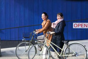 zwei Frauen, die mit ihren Fahrrädern die Straße hinuntergehen in der Unterkunft Umikara in Unzen