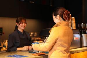 zwei Frauen stehen an einer Theke in einem Restaurant in der Unterkunft Umikara in Unzen