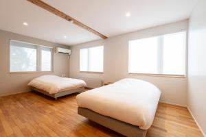 a bedroom with two beds and two windows at Bella Vista Ski Lodge in Nozawa Onsen