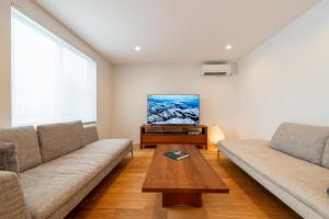 a living room with two couches and a flat screen tv at Bella Vista Ski Lodge in Nozawa Onsen