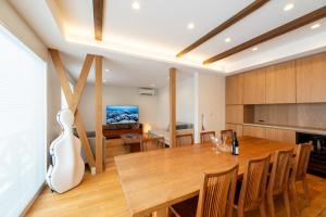 a kitchen and dining room with a wooden table and a guitar at Bella Vista Ski Lodge in Nozawa Onsen