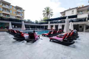 a pool with chairs and umbrellas next to a building at Kleopatra Fatih Hotel in Alanya