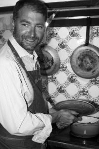 a man in an apron standing in a kitchen at Chambre d'hôtes avec cuisine commune - 5 mns de Narbonne in Cuxac-dʼAude