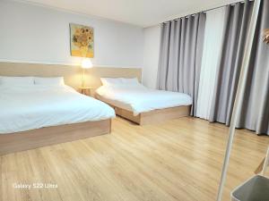 two beds in a hotel room with wooden floors at 상무하우스 in Gwangju