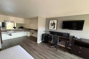 a hotel room with a bed and a desk and a television at Travelodge by Wyndham Hemet CA in Hemet