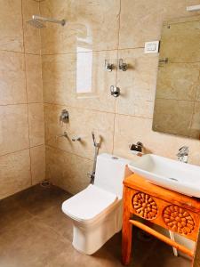 een badkamer met een toilet, een wastafel en een spiegel bij Odbostays Manali in Haripūr
