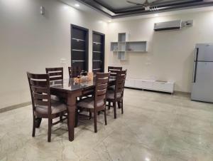 a dining room with a table and chairs and a refrigerator at Shukla Bhawan in Panchkula