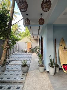a porch with potted plants and a surfboard on it at Blue Mind Surf Home in Weligama