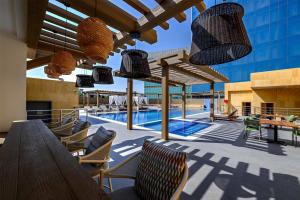 een terras met een zwembad, stoelen en verlichting bij DoubleTree by Hilton Jeddah - Alandalus Mall in Jeddah +117 foto's