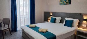 een slaapkamer met een groot bed met blauwe kussens bij Boston Hotel in Yakkasaray