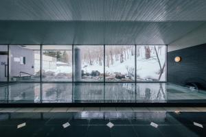 een gebouw met een zwembad met glazen ramen en sneeuw bij Otaru Asari Classe Hotel in Otaru