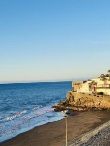 a beach with the ocean and buildings in the background at El Alba in San Bartolomé de Tirajana