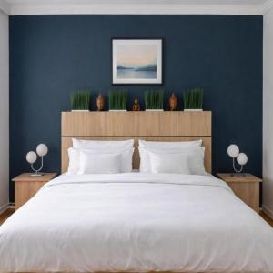 een slaapkamer met een groot wit bed met planten aan de muur bij Comfort 28 Parkside Comfort in Miskolc