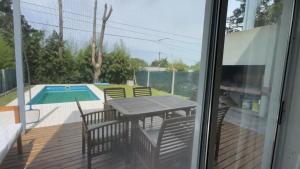 een terras met een tafel en stoelen en een zwembad bij Homero duplex in Villa Gesell