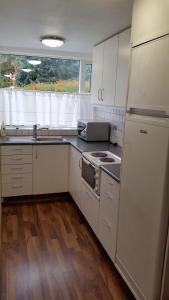 a kitchen with white cabinets and a sink and a refrigerator at Selfoss Apartment in Selfoss