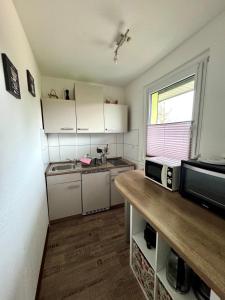 eine kleine Küche mit weißen Schränken und einer Mikrowelle in der Unterkunft Ferienbungalow Muranko am Kiessee in Krugsdorf