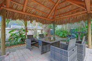 a patio with a table and chairs under a straw roof at Tropical Oasis Studio w Pool in Fort Lauderdale