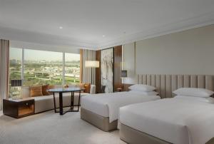 ein Hotelzimmer mit zwei Betten und einem Tisch in der Unterkunft Grand Hyatt Dubai in Dubai