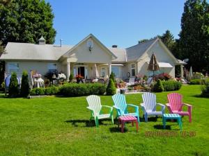 a group of chairs sitting in the grass in front of a house at Willowmere in Cobourg