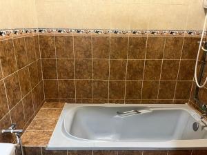 een badkamer met een ligbad en bruine tegels bij LIY Homestay in Gua Sai +15 foto's