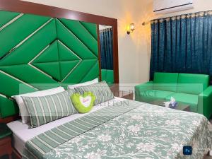 een groene slaapkamer met een bed en een groen hoofdeinde bij Hotel White Palace Clifton in Karachi