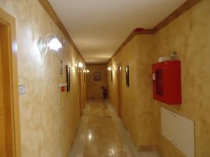 un long couloir avec une boîte rouge sur un mur dans l'établissement Hotel Antequera Rural Fortes La Nuit, à Mollina