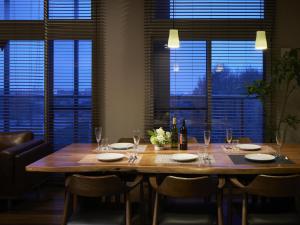 een houten tafel met stoelen, wijnflessen en glazen bij Minn Chitose in Chitose