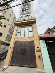 a building with a brown door with people on a balcony at Cozy Homestay Tây Mỗ in Phú Thú