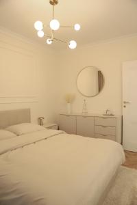una camera da letto bianca con un letto e uno specchio di Apartamenty Villa Piano a Ostrołęka