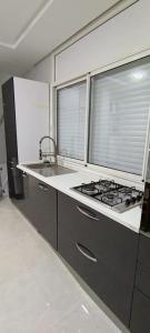 een keuken met een fornuis, een wastafel en 2 ramen bij Temara wifak in Temara