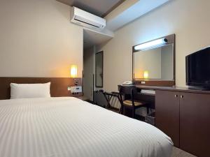 ein Hotelzimmer mit Bett, Schreibtisch und Fernseher in der Unterkunft Hotel Route-Inn Ichinoseki Inter in Ichinoseki + 29 Fotos