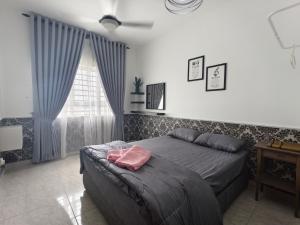 a bedroom with a bed and a table and a window at Cocasa Homestay 1 in Kuala Terengganu