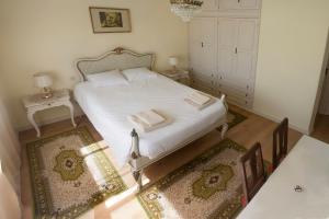 a bedroom with a white bed with two rugs at Burgo's House in Porto