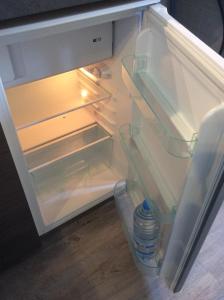 - un réfrigérateur ouvert avec une bouteille d'eau dans l'établissement Appart Hôtel l'Orchidée, à Morangis