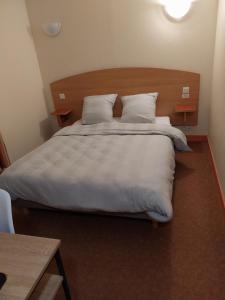 a bedroom with a large bed with white sheets and pillows at Hôtel le beau séjour in Sainte-Suzanne