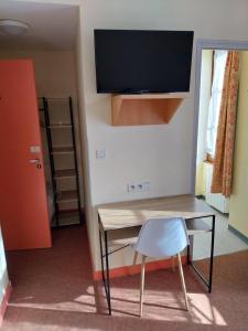 a room with a desk and a chair and a television at Hôtel le beau séjour in Sainte-Suzanne