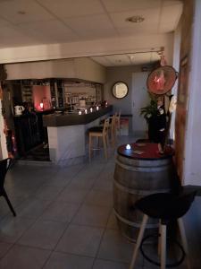 a bar with a wine barrel and a table and chairs at Hôtel le beau séjour in Sainte-Suzanne