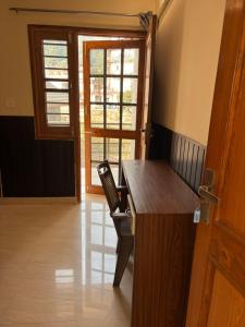 a room with a desk with a chair and a window at Hathayogashram Hostel in Rishīkesh