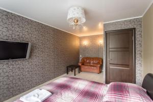 a bedroom with a bed and a television and a chair at Apartment 2Pillows Vorovskogo in Vologda