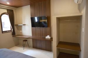 una camera da letto con un letto e una TV a parete di Avaya Boutique Hostel by Ayodya Beach Inn a Legian