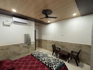 a bedroom with a bed and chairs and a ceiling fan at Hotel Utsav in Khatīma