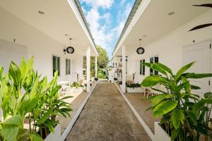 a hallway of a white building with plants at Peridot Pool Beach in Chaweng Noi Beach