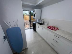a kitchen with white cabinets and a blue chair at Coastal Escape in North Coast